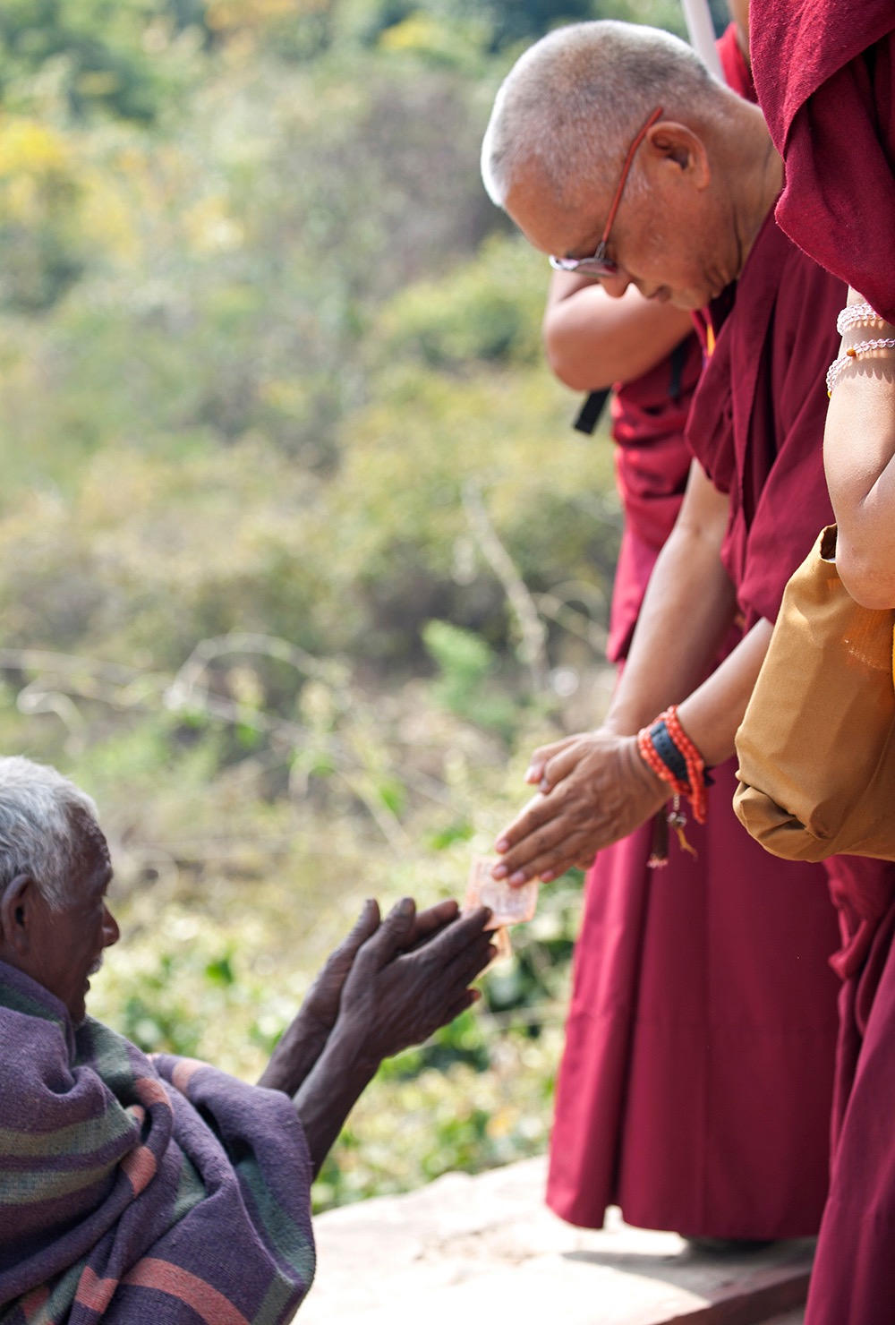 Rinpoche making charity respectfully to a beggar at Vulture’s Peak, India. (Photo Andy Melnic)
