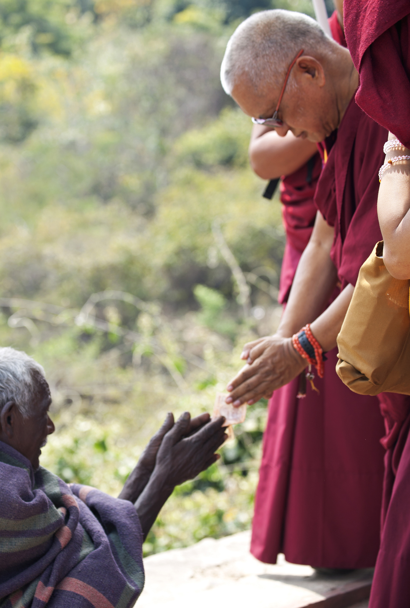 Lama Zopa Rinpoche respectfully offers to a beggar on the way up to Vulture’s Peak, Rajghir, March 2014. (Photo Andy Melnic)