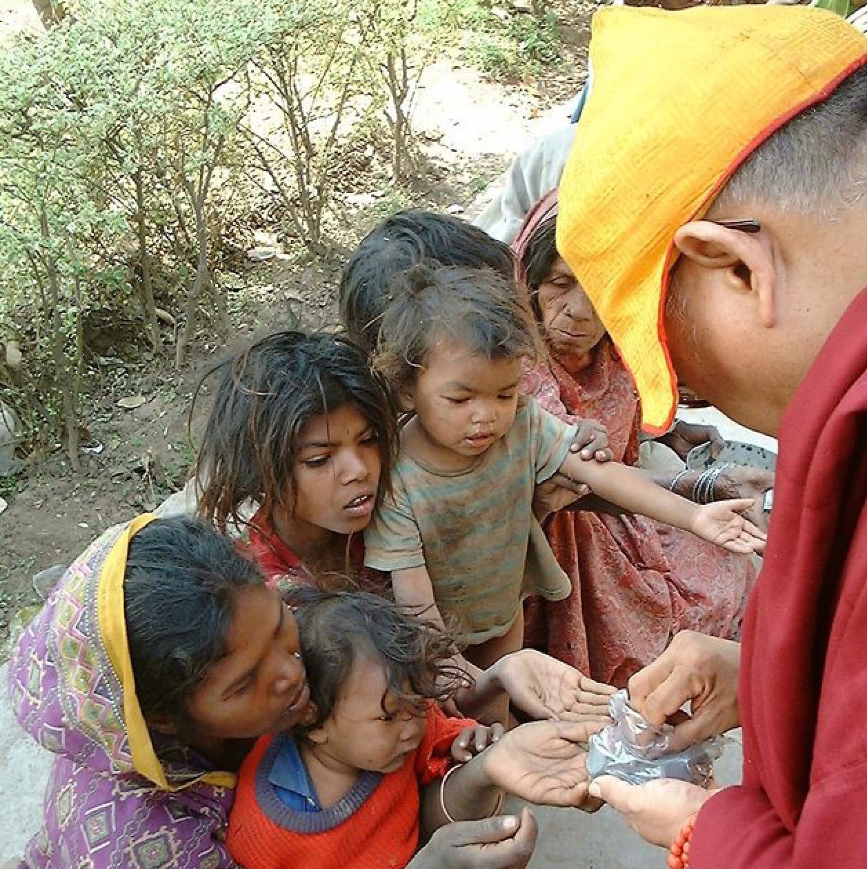 Rinpoche giving to the beggars in India. (Photo Ven Roger Kunsang)